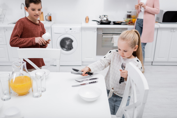 a gyerekek a konyhában terítenek, míg a nagyi reggelit készít - Fotó, kép