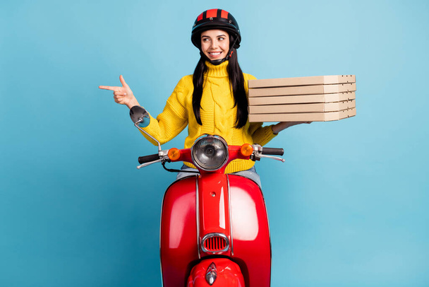 Photo portrait of female delivery worker keeping pizza boxes pointing on copyspace sitting on red bike isolated bright blue color background. - Foto, immagini