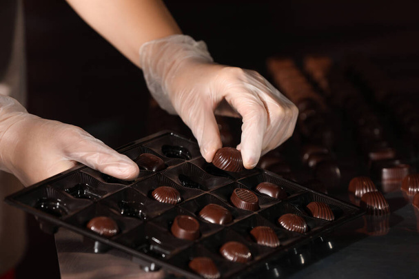 Woman packing delicious candies at production line, closeup - Zdjęcie, obraz