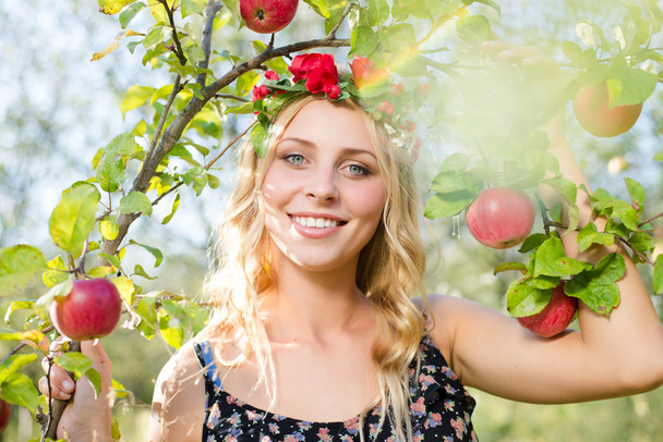 Blond girl smiling among red apples - Photo, Image