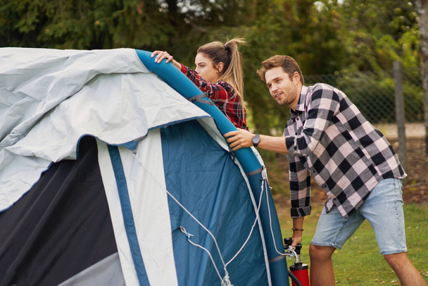 Young nice couple having fun on camping setting up tent - Foto, imagen