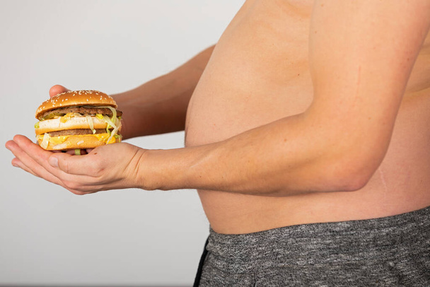 Photo of a man's hand holding a cheeseburger  - Fotografie, Obrázek