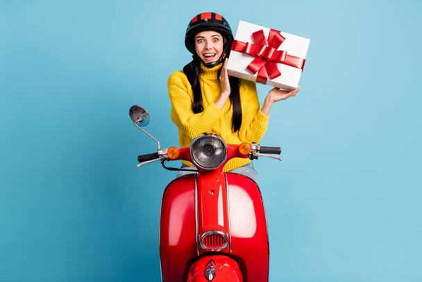 Photo portrait of amazed surprised girl on retro bike interested trying to guess whats inside gift box isolated vivid blue color background - Foto, Imagem