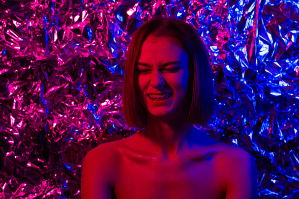 Portrait of a beautiful girl in neon light of purple, pink and blue colors. Young woman in a futuristic look. - Fotó, kép
