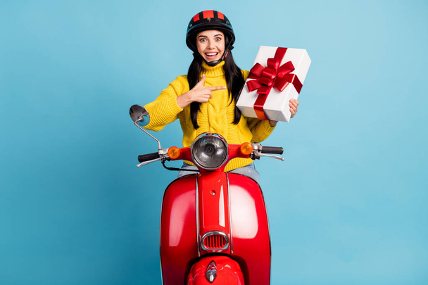 Photo of lady drive moped hold giftbox közvetlen mutatóujj kopás sárga pulóver sisak elszigetelt kék háttér - Fotó, kép