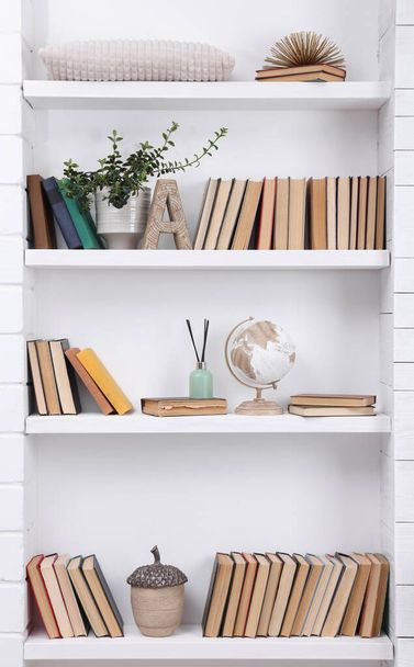Collection of books and decor elements on shelves indoors - Fotografie, Obrázek