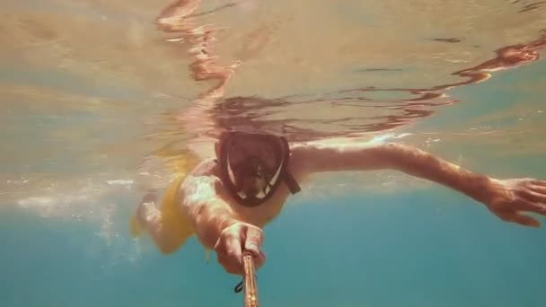 Egy férfi búvár a kamera előtt lelövi magát a víz alatt. Víz alatti lövöldözés sekély vízben. - Felvétel, videó