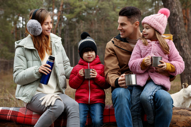 Onnellinen perhe kuumien juomien kanssa viettää aikaa yhdessä metsässä - Valokuva, kuva