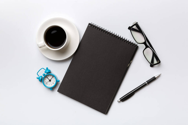 Modern office desk table with notebook and other supplies with cup of coffee. Blank notebook page for you design. Top view, flat lay. - Photo, Image