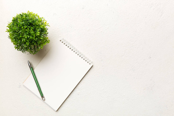 Modern office desk table with notebook and other supplies with green tree. Blank notebook page for you design. Top view, flat lay. - Photo, Image