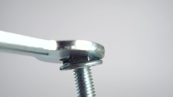 Una llave de acero aprieta una tuerca de perno sobre un fondo blanco. Macro tiro - Imágenes, Vídeo