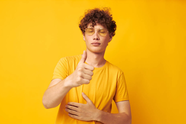 Young curly-haired man yellow t-shirt glasses fashion hand gestures monochrome shot - Foto, immagini