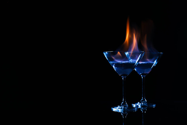 Cocktail glasses with flaming vodka on black background, space for text - Foto, Bild