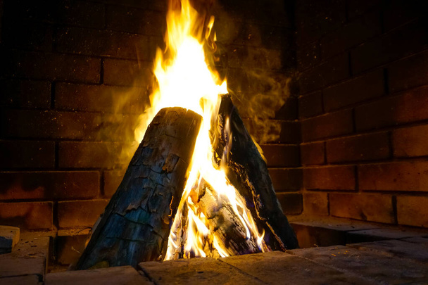 Bright warm fire in a brick fireplace in the house - 写真・画像