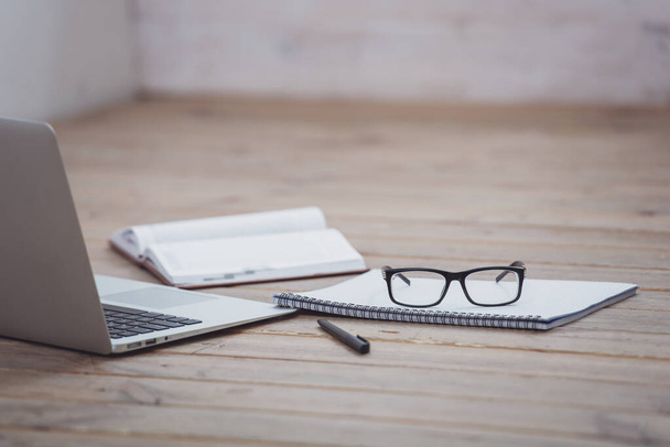 Laptop, eyeglasses and some office supplies on wooden surface - Photo, Image