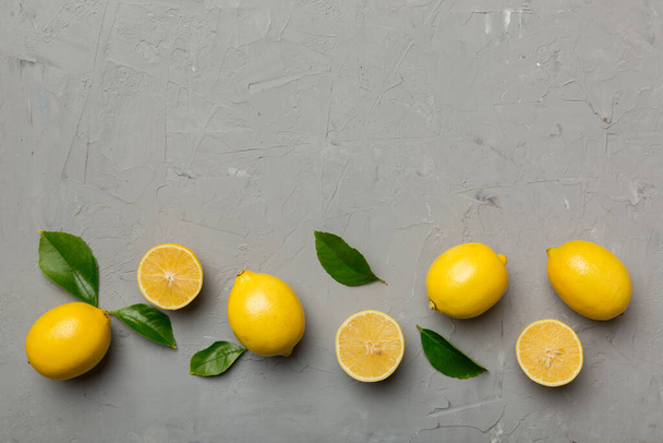 Многие свежие спелые лимоны с зелеными листьями на цветном фоне, вид сверху, пространство для текста. - Фото, изображение