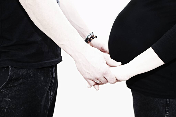 Young couple holding hands. They are expecting a child.Woman in 8 months pregnant holding her husband`s hands. - Photo, Image