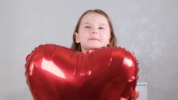 little cute girl in a red dress holding red heart-shaped balloons in her hands concept of valentines day - Video