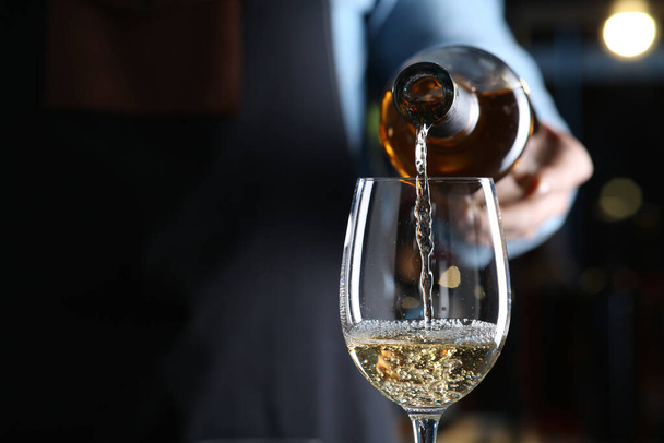 Bartender pouring white wine from bottle into glass indoors, closeup. Space for text - Foto, Imagen