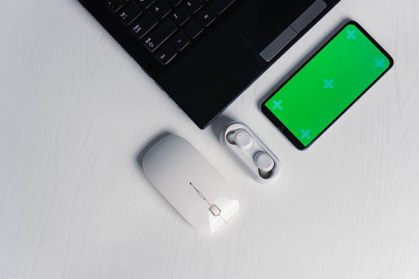 Piatto lay shot di gadget e dispositivi mobili in background bianco. Smartphone schermo verde mockup - Foto, immagini