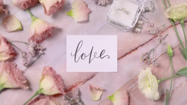 SZERETET kártya egy márvány asztal közelében rózsaszín virágok felső nézet nagyítás  - Felvétel, videó