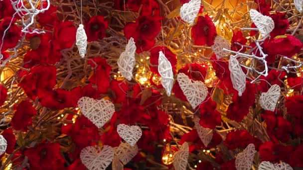 Saint-Valentin économiseur d'écran. Décorations blanches en forme de coeur suspendues à une balançoire d'arbre et de spin soufflé par le vent sur le fond de lumières éclairantes et de branches sèches avec des fleurs - Séquence, vidéo