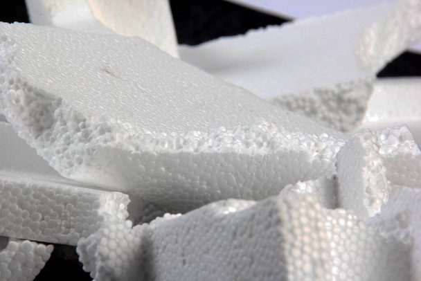 Styrofoam Sheets of different shapes on black background. Pieces of white styrofoam close up. Crumbled styrofoam pieces isolated on dark background - Photo, Image