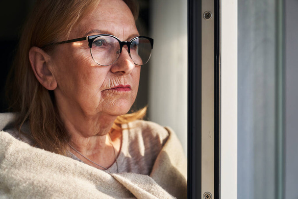 Caucásico mujer mayor con depresión mirando tirar la ventana  - Foto, imagen