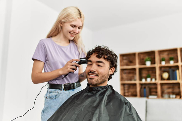 Молодая женщина стрижет волосы своему парню дома. - Фото, изображение