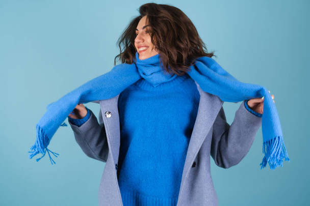 Kevään syksyn muotokuva naisesta sinisessä neulotussa villapaidassa, huivissa ja harmaassa takissa, poseeraa iloisesti, hymyillen, ennakoiden kevättä. - Valokuva, kuva
