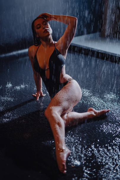 Woman in bikini sitting in aqua studio under rain drops - 写真・画像