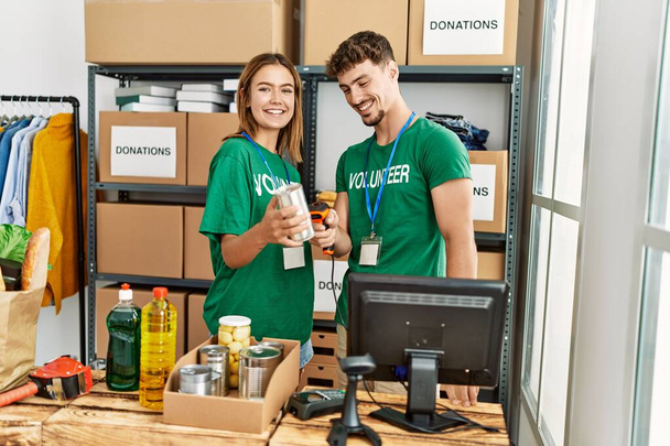 Giovane coppia di volontari ispanici sorridente felice di lavorare al centro di beneficenza. - Foto, immagini