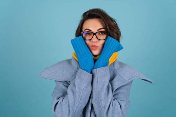 Spring autumn portrait of a woman in a blue knitted sweater, glasses, a yellow bright scarf and a gray coat, smiling cheerfully, posing fashionably, in anticipation of spring - Photo, Image