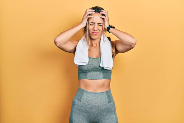Beautiful hispanic woman wearing sportswear and towel suffering from headache desperate and stressed because pain and migraine. hands on head.  - Photo, Image