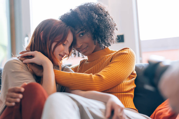 women lesbian couple in backlight hugging on the sofa - Photo, Image