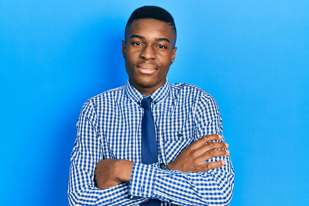 Молодий афроамериканець у діловій сорочці і краватці щасливим обличчям посміхається з перехрещеними руками, дивлячись на камеру. позитивна людина.  - Фото, зображення