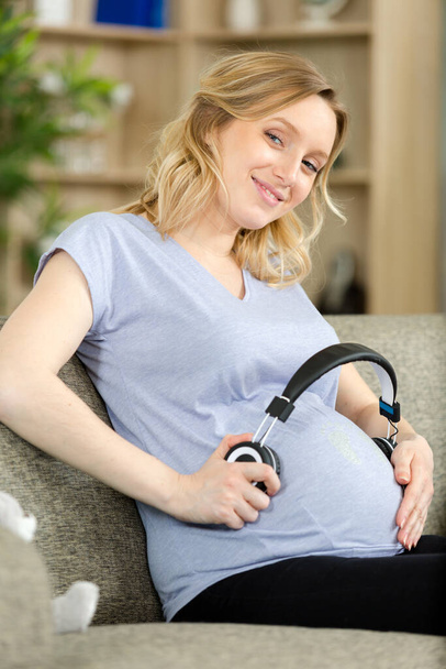 close up of headphones on pregnant belly - Фото, изображение