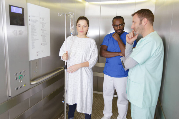 médicos do sexo masculino e paciente do sexo feminino no elevador - Foto, Imagem