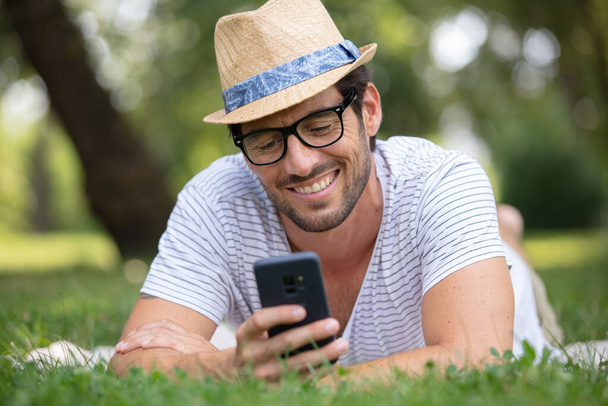 handsome man on the grass texting his date - Zdjęcie, obraz