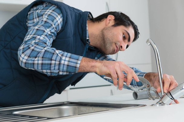 a plumber removing kitchen faucet - Foto, immagini