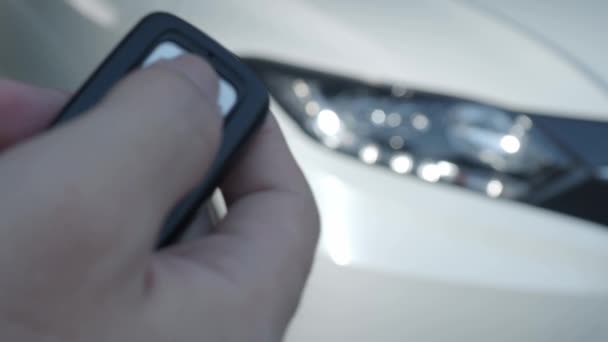 Car key remote control. Locking and unlocking the car by the car key remote control. Pressing the button of the car key and the lights blink when door opens or closed. Man hand using auto remote key. - Footage, Video