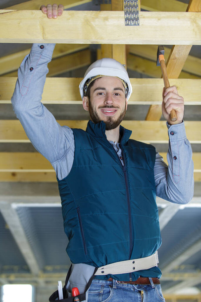 male builder on the roof of a wooden frame house - Foto, Bild