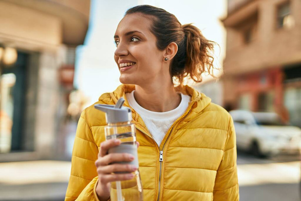 Giovane ragazza ispanica sorridente bottiglia di acqua potabile felice alla città. - Foto, immagini