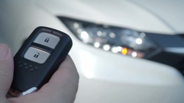 Auton avain kaukosäädin. Auton lukitseminen ja avaaminen auton avaimen kaukosäätimellä. Auton avaimen painallus ja valot vilkkuvat, kun ovi aukeaa tai sulkeutuu. Mies käsi automaattisen etäavaimen avulla. - Materiaali, video