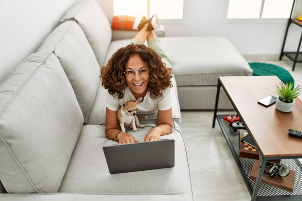 Középkorú spanyol nő mosolyog magabiztos segítségével laptop otthon - Fotó, kép