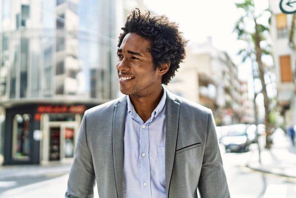 Giovane uomo d'affari afroamericano sorridente felice in piedi alla città. - Foto, immagini