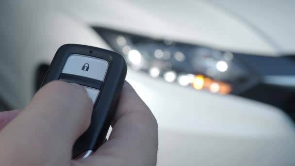 Auton avain kaukosäädin. Auton lukitseminen ja avaaminen auton avaimen kaukosäätimellä. Auton avaimen painallus ja valot vilkkuvat, kun ovi aukeaa tai sulkeutuu. Mies käsi automaattisen etäavaimen avulla. - Materiaali, video