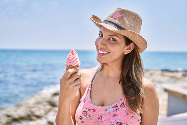 Brunette woman enjoying a summer day at the beach eating an ice cream cone - Photo, Image