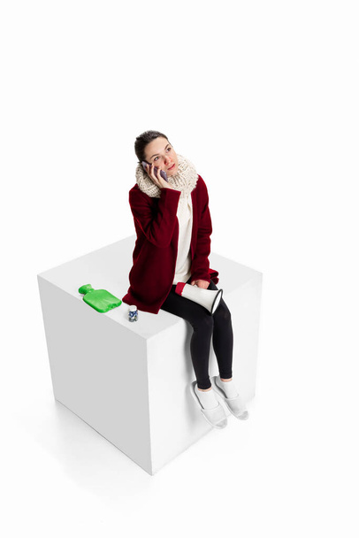 Studio shot of young girl feeling sick, has running nose sitting on box isolated over white background. Flu, cold, allergy - Φωτογραφία, εικόνα
