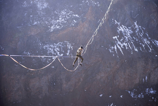 Ένας αθλητής σκαρφαλώνει σε μια ψηλή γραμμή για να φτάσει ψηλά πάνω από μια όμορφη λίμνη. - Φωτογραφία, εικόνα
